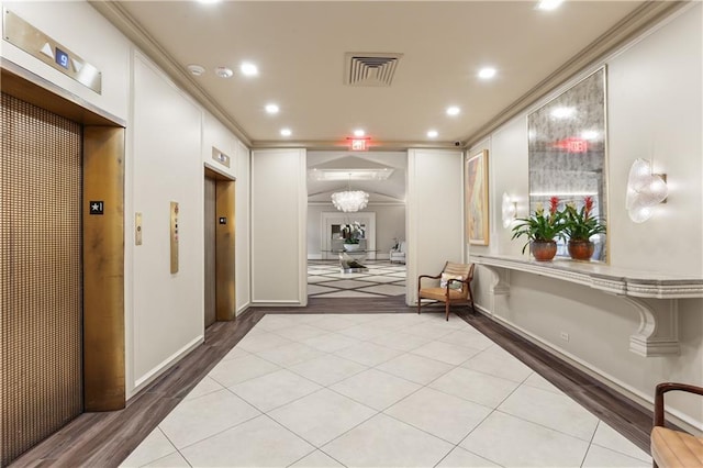 hall with elevator, crown molding, and light hardwood / wood-style flooring