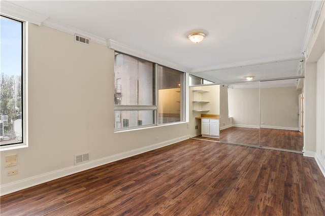 unfurnished bedroom featuring a closet, ornamental molding, hardwood / wood-style floors, and multiple windows