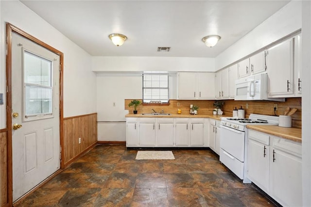 kitchen with sink, white cabinetry, white appliances, and wood walls