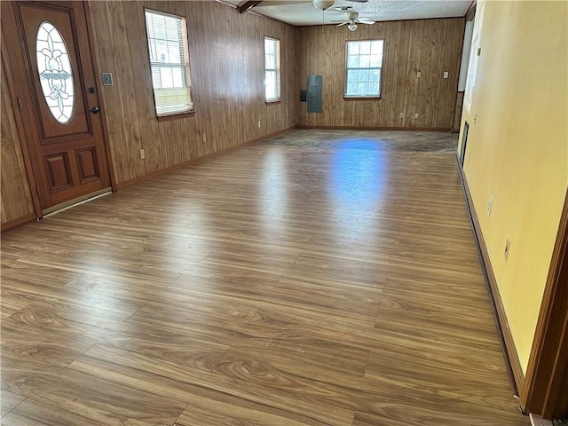 interior space featuring ceiling fan, wood-type flooring, and wood walls