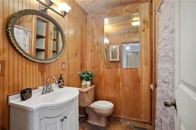 bathroom featuring vanity, toilet, and wooden walls