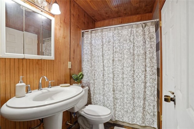 bathroom featuring toilet, wooden walls, wooden ceiling, sink, and a shower with shower curtain