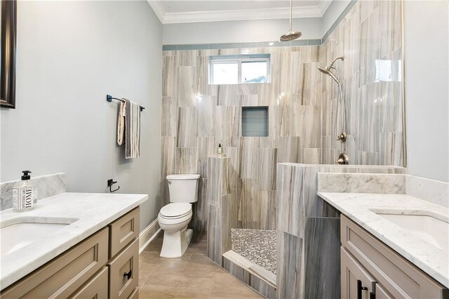 bathroom with tile patterned flooring, toilet, a tile shower, vanity, and ornamental molding