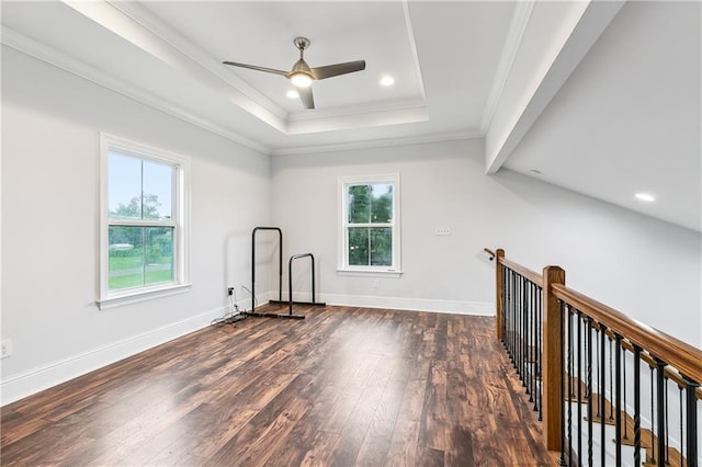 unfurnished room featuring a healthy amount of sunlight, ornamental molding, a tray ceiling, and hardwood / wood-style flooring