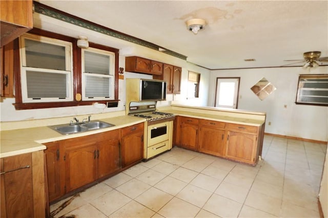 kitchen featuring sink, light tile patterned floors, kitchen peninsula, ceiling fan, and white gas range oven