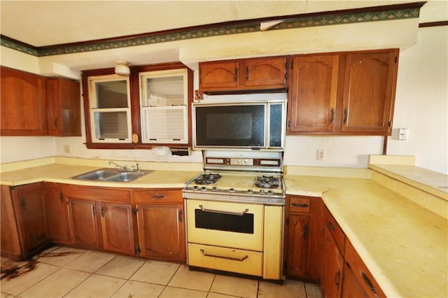 kitchen with white gas range, sink, and light tile patterned floors