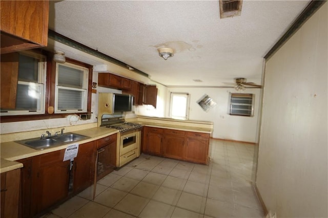 kitchen featuring a textured ceiling, appliances with stainless steel finishes, kitchen peninsula, sink, and ceiling fan