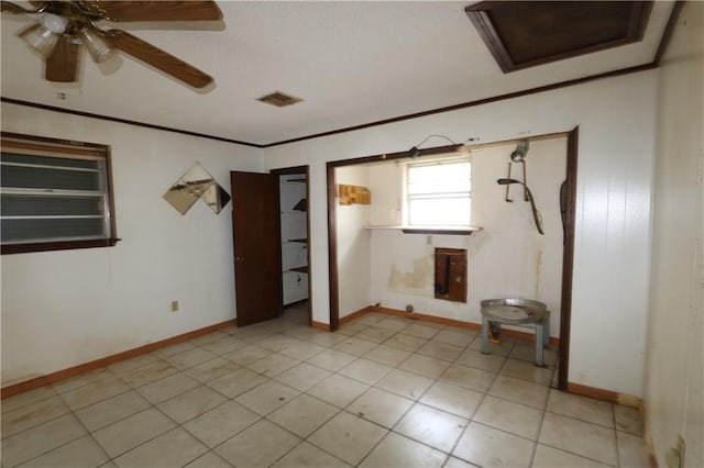 tiled empty room featuring ceiling fan and ornamental molding