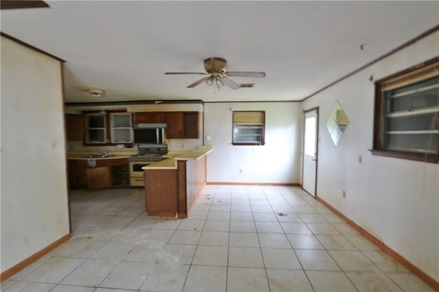 kitchen with gas range oven, ceiling fan, light tile patterned floors, and crown molding