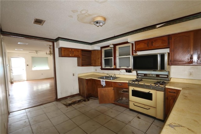 kitchen featuring white range with gas stovetop, light tile patterned floors, a textured ceiling, and sink