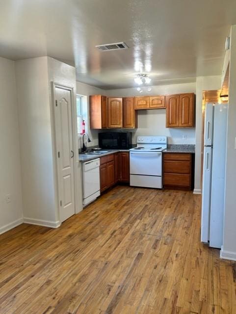 kitchen with white appliances, light hardwood / wood-style flooring, and sink