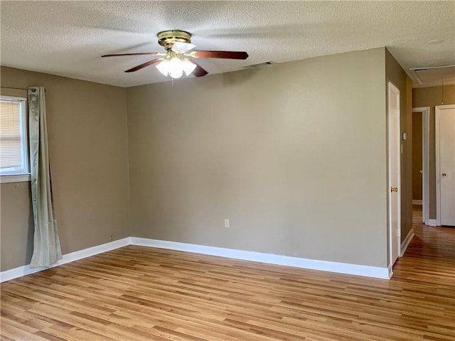 empty room with ceiling fan, light hardwood / wood-style floors, and a textured ceiling