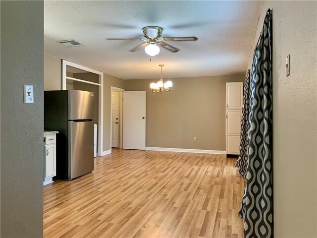 kitchen with light hardwood / wood-style flooring, ceiling fan with notable chandelier, stainless steel fridge, and white cabinetry