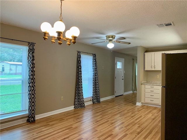 interior space with white cabinets, stainless steel fridge, pendant lighting, and light hardwood / wood-style floors