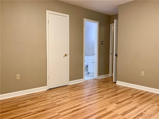 unfurnished bedroom with ensuite bath and light hardwood / wood-style floors