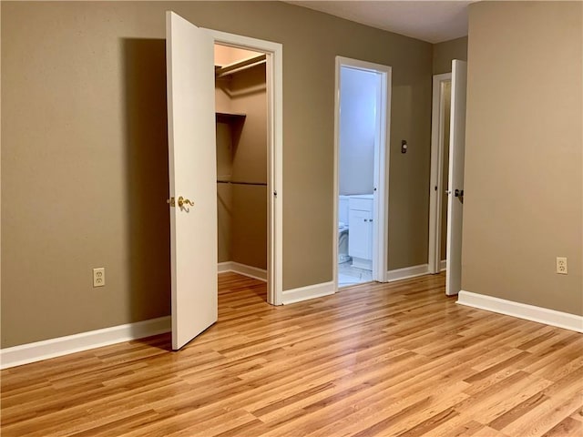 unfurnished bedroom with a closet, a spacious closet, and light hardwood / wood-style flooring