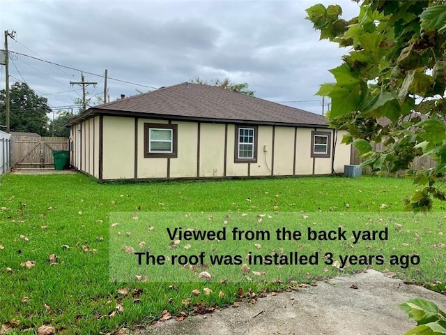 rear view of property featuring cooling unit and a yard