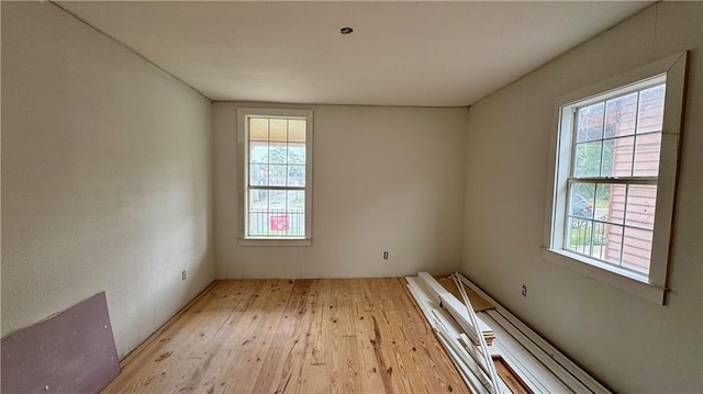 empty room with light hardwood / wood-style floors and plenty of natural light