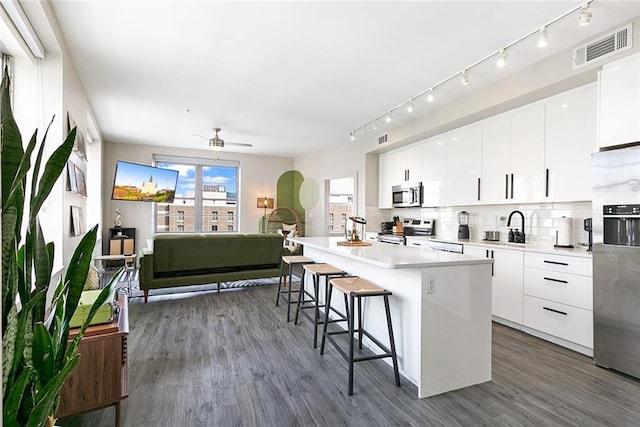 kitchen with appliances with stainless steel finishes, a kitchen island, white cabinetry, and ceiling fan