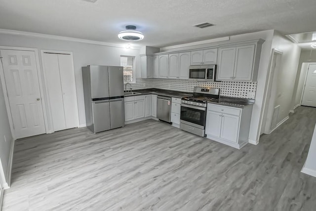 kitchen with gray cabinets, appliances with stainless steel finishes, backsplash, and light hardwood / wood-style flooring