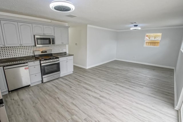 kitchen with crown molding, light hardwood / wood-style flooring, backsplash, appliances with stainless steel finishes, and gray cabinetry