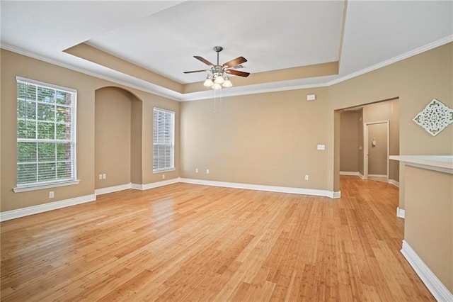 unfurnished room featuring ceiling fan, ornamental molding, light wood-type flooring, and a tray ceiling