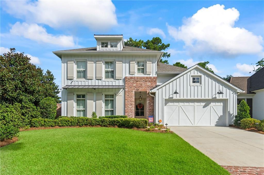 view of front facade with a front yard, driveway, a garage, board and batten siding, and brick siding