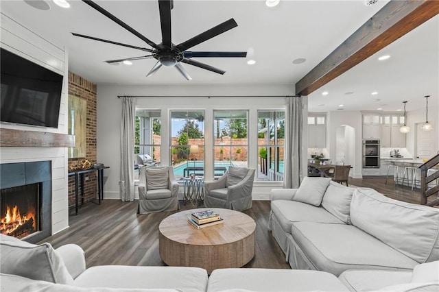 living room with dark hardwood / wood-style flooring, ceiling fan, and beamed ceiling