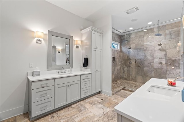 bathroom with tiled shower and vanity