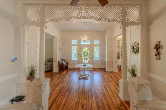 foyer featuring decorative columns, hardwood / wood-style flooring, and a notable chandelier