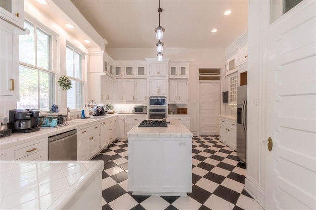 kitchen featuring tile counters, stainless steel appliances, and white cabinets