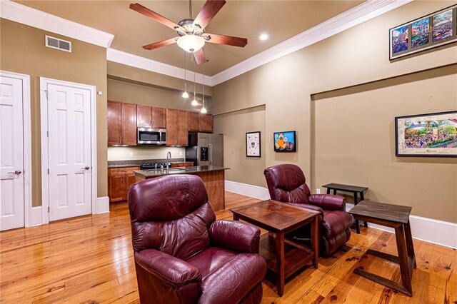 interior space with ceiling fan, sink, crown molding, and light hardwood / wood-style flooring