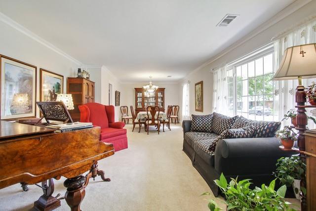 living room with a notable chandelier, crown molding, and carpet floors