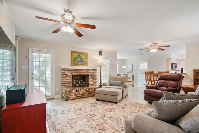 living room featuring ceiling fan and a brick fireplace