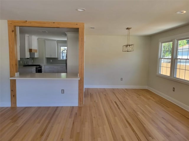 kitchen featuring light wood-style flooring, stainless steel range with gas stovetop, baseboards, and a wealth of natural light