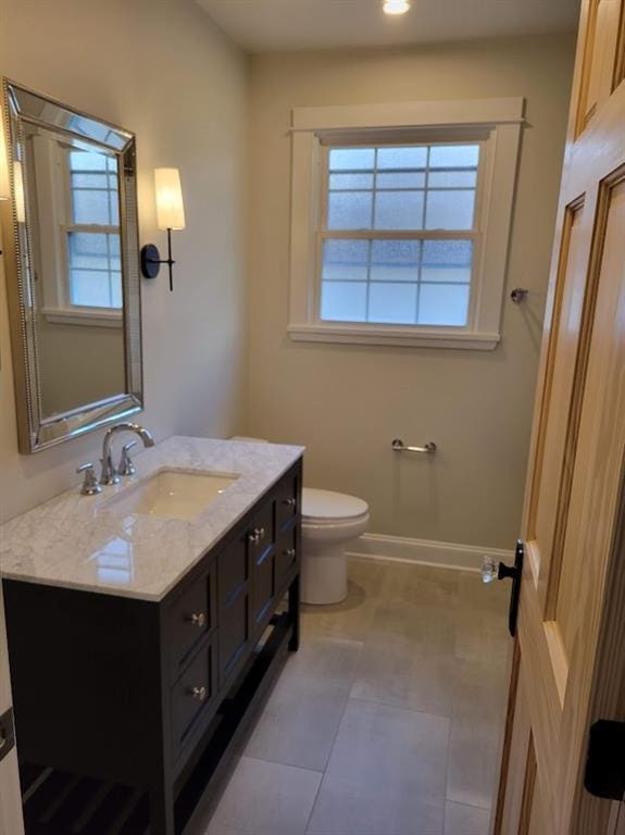 bathroom featuring a wealth of natural light, toilet, vanity, and baseboards