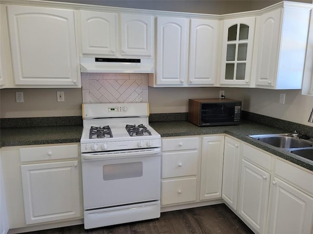 kitchen with under cabinet range hood, dark countertops, white cabinets, and white gas range oven