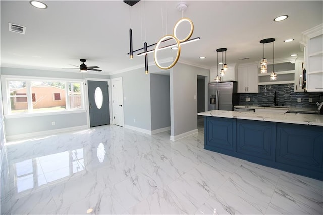 kitchen featuring stainless steel refrigerator with ice dispenser, sink, white cabinetry, light stone counters, and hanging light fixtures