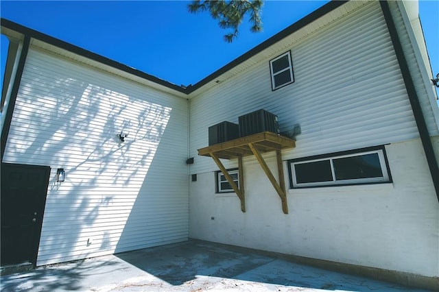 view of side of property featuring a balcony, a patio, and central air condition unit