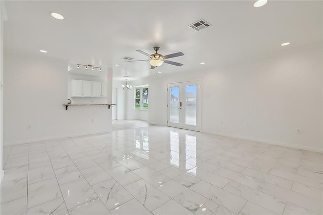 empty room featuring ceiling fan with notable chandelier