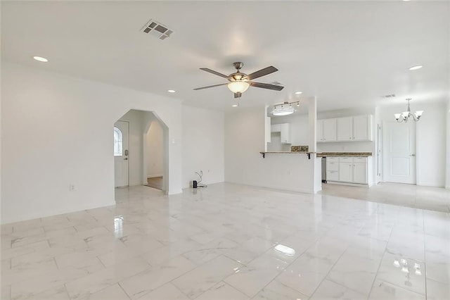 unfurnished living room with ceiling fan with notable chandelier