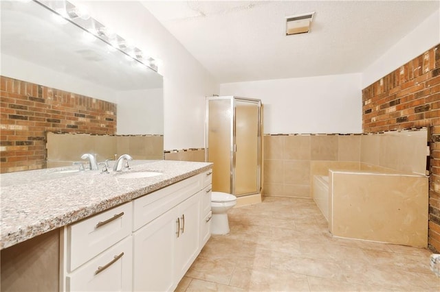 bathroom with a shower with door, vanity, brick wall, tile walls, and toilet