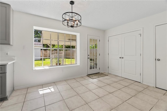 interior space featuring a textured ceiling, an inviting chandelier, and light tile patterned flooring