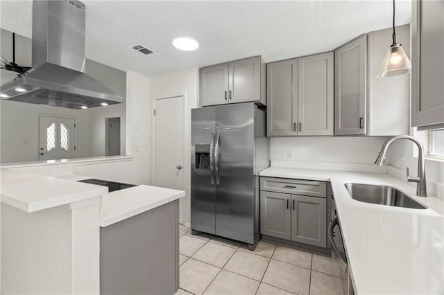 kitchen featuring kitchen peninsula, stainless steel fridge, sink, wall chimney range hood, and gray cabinets