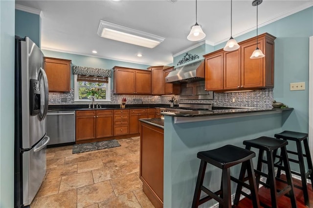 kitchen featuring decorative light fixtures, stainless steel appliances, sink, a breakfast bar, and wall chimney exhaust hood