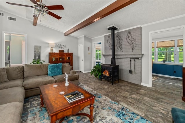 living room with lofted ceiling with beams, plenty of natural light, ceiling fan, and a wood stove