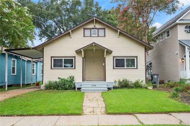 bungalow-style home with a carport and a front lawn