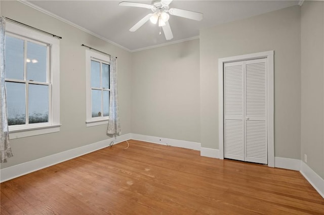 unfurnished bedroom with hardwood / wood-style flooring, ceiling fan, crown molding, and a closet