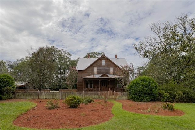 back of property with a yard, fence, and covered porch