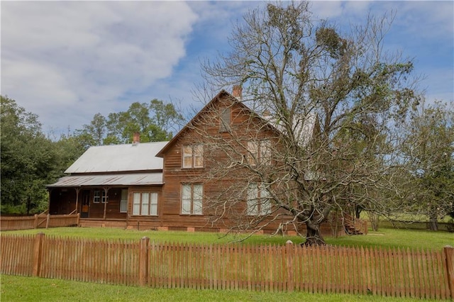 view of front of property featuring a chimney, fence private yard, and a front lawn